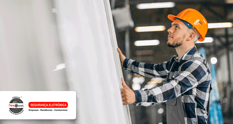 Um homem usando capacete e macacão instalando um portão