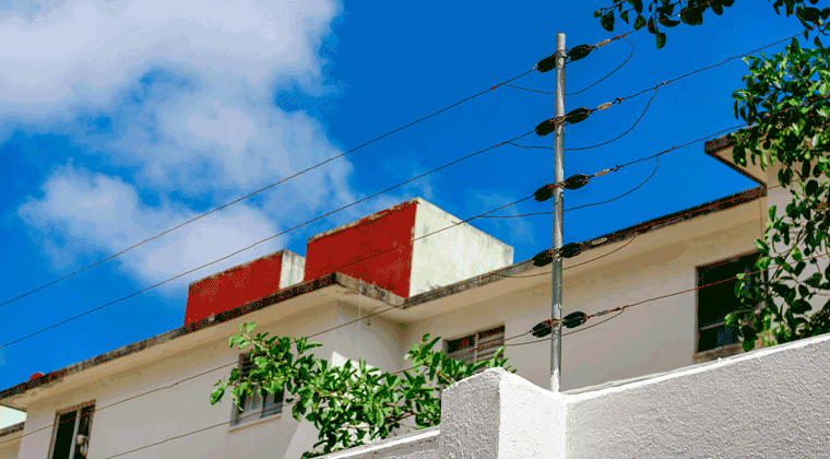 Cerca elétrica com uma casa e o céu azul ao fundo