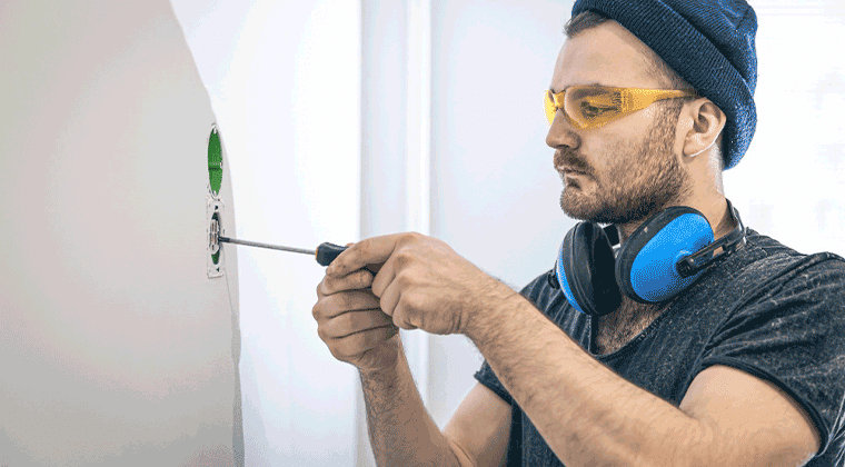 Um homem usando itens de segurança e segurando uma chave de fenda