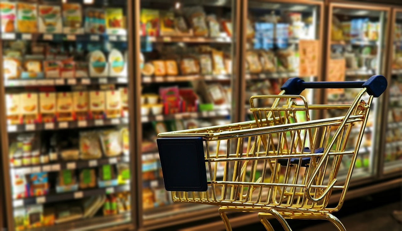 Carrinho de supermercado com geladeiras ao fundo