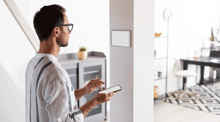 Homem segurando um celular enquanto olha para uma tela na parede